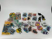 Photo showing entire group of 28 McDonald's Batman-themed toys including several action figures, vehicles, and small packaged toys.