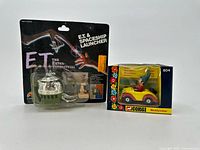 Two sealed vintage toys displayed side by side: E.T. Spaceship Launcher blister card and Noddy's Car boxed toy.