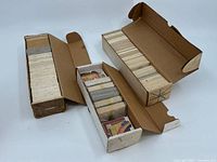 Three open cardboard boxes filled with multiple stacks of baseball puzzle cards.