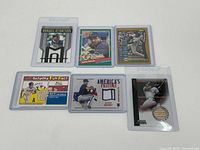 Group of 6 baseball sports cards laid out on a white surface, showing front and back sides including a Bowman Sterling card with embedded bat piece.