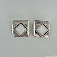 Front view of the pair of square sterling silver earrings with white center stones.