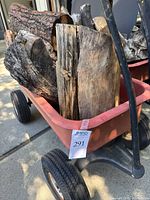 Photo of one red Radio Flyer wagon filled with firewood on driveway showing metal pull handle and wheels.