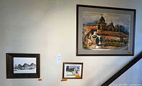 Three framed paintings on a wall, showing a large Mission Dolores painting and two smaller nature scene paintings.