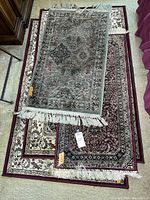 Stack of four Persian style area rugs with visible fringes, different sizes and colors, including Roma rug 45x25 inches on top