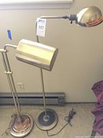 Full view of the two brass floor lamps side by side showing one with a cylindrical shade and one with a dome-shaped shade.