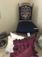 View of antique upholstered accent chair with needlepoint backrest and navy blue seat, showing carved painted wood frame and dimensions tag.