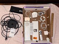 Full view of Apple TV unit with cables and accessories in a box.