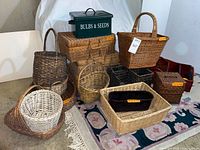 Multiple wicker baskets of various shapes and sizes including rectangular, square, and round with different colors and materials, also green metal storage tin labeled 'BULBS & SEEDS'