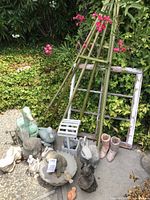 Wide shot of assorted outdoor garden statues and decor on pavement with plants background