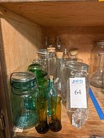 Photo showing approx. 14 assorted vintage glass bottles and jars, various colors and closures.