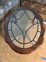 Top view of oval coffee table showing stained glass design on glass top and wooden edge.