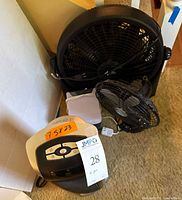 Photo showing four items: large black floor fan, small black table fan, white portable space heater, and white Arctic Air Ultra cooler.