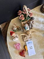 Side view showing porcelain figurines including elderly couple and floral basket, with three glass heart paperweights at front.
