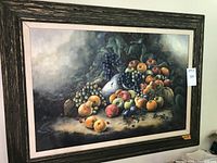 Framed oil painting showing an assortment of fruits like peaches, grapes, apples, and other fruits in a dark color palette.