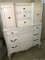 Front view of the dresser showing the six drawers and two cabinet doors with vintage hardware and ornate carvings