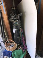 Golf clubs in black bag with golf towels hanging and golf balls basket visible