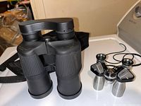 Pair of black Simmons Model 1183 8x12 binoculars with rubber grip and neck strap.