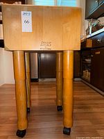 Front view showing Boos Block logo on butcher block surface and four legs with casters