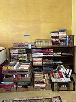 Full view of books arranged on a bookshelf and in multiple cardboard boxes on the floor.