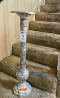 Full front view of white marble pedestal stand on carpeted stairs