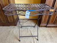 Front view of metal side table with lattice surface showing ornate pattern and structural details.