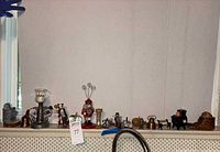 Wide view showing all miniature figurines and decorative items lined up on a shelf.