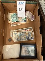 Photo of box with mixed foreign currency bills and a loose Canadian coin visible