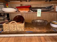 Shelf showing various serving bowls and platters including woven basket, glass bowl, ceramic bowls, and wooden platters