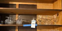 Wide view of mixed set including clear and cut crystal glasses on wooden shelf