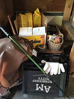 Photo showing vintage brown backpack, black stadium seat labeled 'AM Archishop Mitty', fire starters and logs, green trekking pole, white gloves and basket with small items