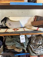 Shelved display of folded saddle blanket, rope girth strap, and Fieldline Realtree game and shell carrier with pouches below.