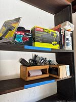 Shelves holding boxed power tools including Makita BO4550 sander, Ryobi One+ drill set, and other hand tools and accessories.