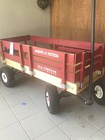 Side view showing the red wooden wagon body with removable sides, Radio Flyer branding, and large air tires.
