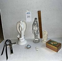 Wide group photo showing all religious figurines and decor pieces arranged against a white background, including porcelain, glass, and wooden items.
