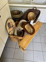 Lot contents including US flag wall clock, antiqued brass planter, beechwood shelf riser, multiple wicker baskets, and framed mirror.