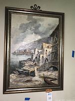 Full view of oil painting depicting a cloudy seaside village with boats on shore and buildings along the water.