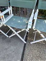 Front and side view close-up of one light green canvas wooden director's chair showing seat, backrest and folded leg cross supports.