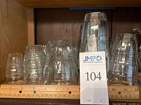 Glassware set of clear ribbed glasses, various sizes including tumblers and juice glasses laid out in shelf space.