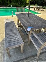 Overall view of teak table, benches, chairs, umbrella and base by pool