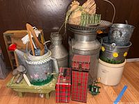 Wide angle shot showing entire lot including milk can, watering can, stoneware crock, wooden crates and green stool