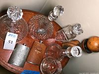 Top-down view showing large and medium crystal decanters, small clear glass decanter, and two flasks laid out on a round table.