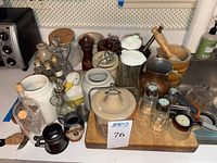 Front view of the vintage stoneware crocks, glass jars, and metal kitchen items arranged on trays.