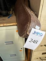 Closed, worn brown violin case with visible scuffs and damage on bottom corner.