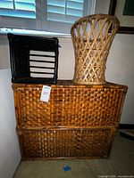 Three items including two stacked medium brown wicker shelf units and a tall cylindrical rattan basket with open lattice design on top.