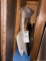 Side view showing stacked serving trays and platters of wood and ceramic, tagged for sale.