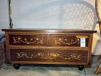 Full chest view showing three drawers with floral inlay and brass-tone handles, overall good condition.