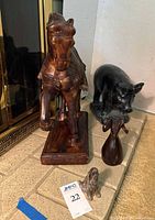 Four animal sculptures arranged on a stone surface near a fireplace: wooden ram head, metal dog, wooden horse on base, and ceramic pig.