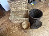 Overview of three wicker containers including rectangular chest, cylindrical hamper with lid, round basket