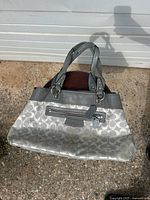 Front view of grey Coach Penelope tote showing signature canvas, leather trim, handles, and front zipper pocket