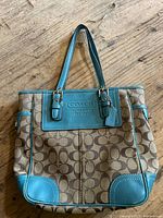 Front view of Coach canvas tote showing turquoise leather trim and signature C pattern